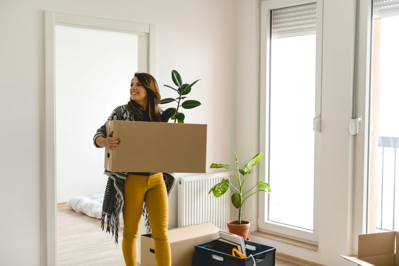 A woman carries a box into a new home.