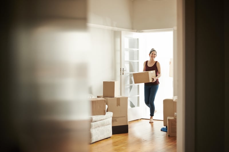 A woman carries boxes into a new home.