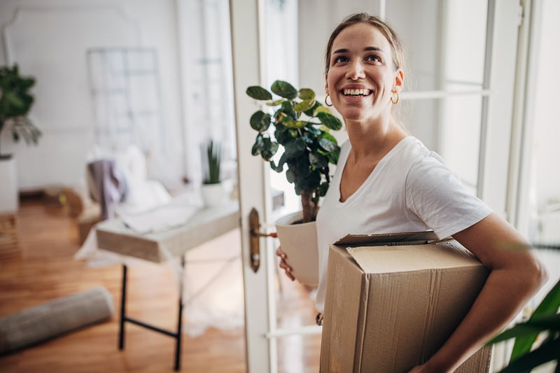 A woman carries boxes into a new house.