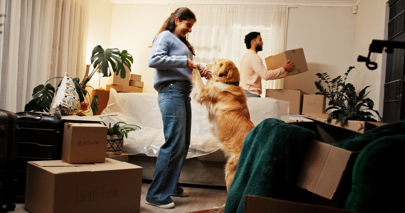 A woman hold hands with her dog while moving into a new house.