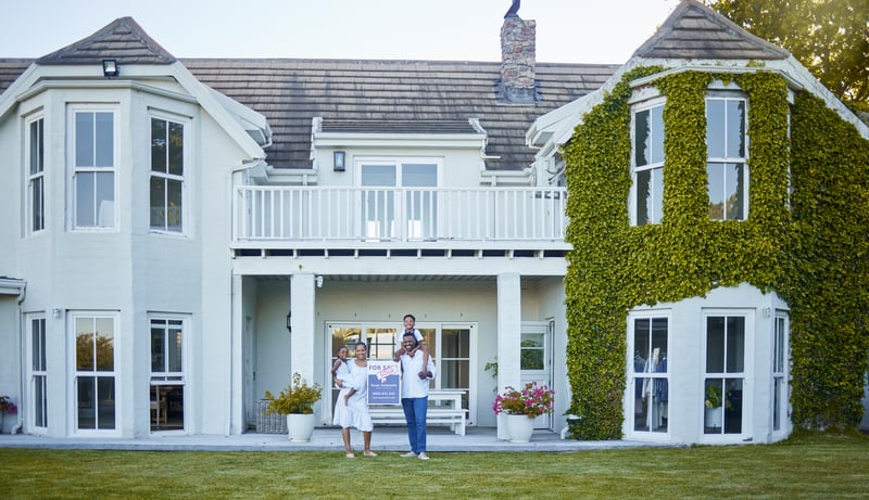 People stand outside of a large home.