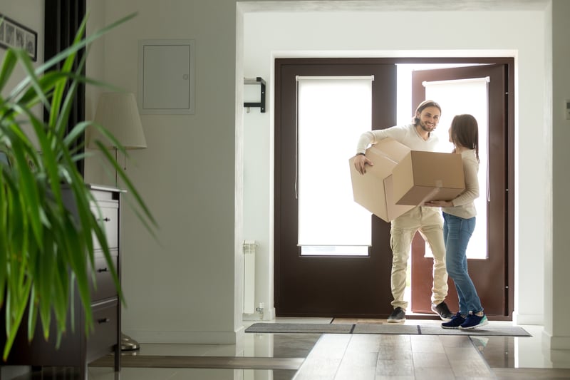 People carry boxes into their new home.