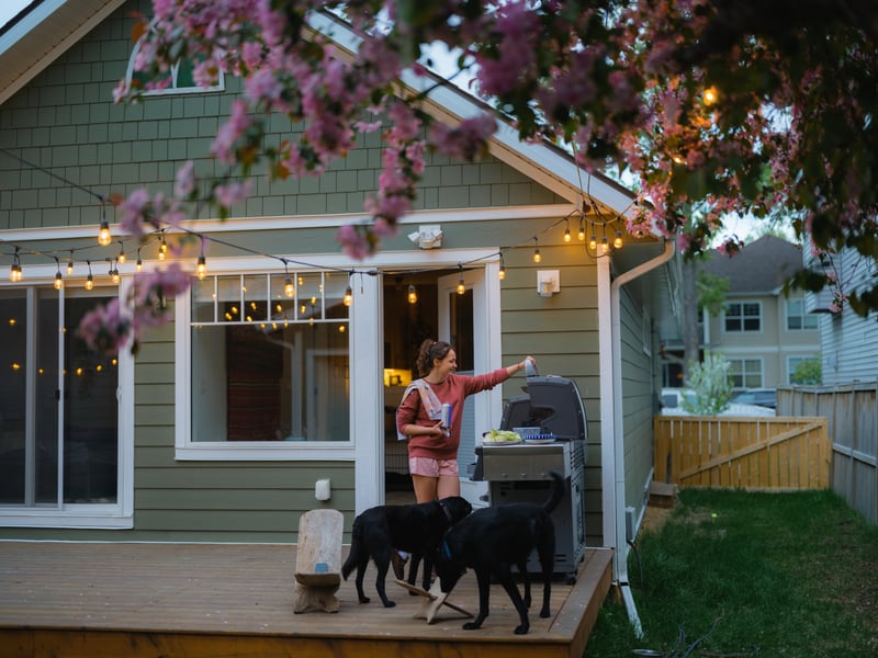 A first-time homebuyer grills out with two black labs.