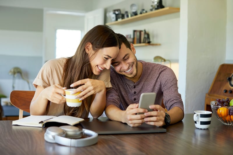 A man and a woman smiling and looking at a phone.