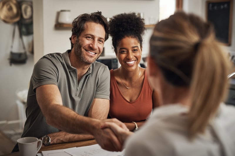 A man and a woman shake hands with a real estate agent.