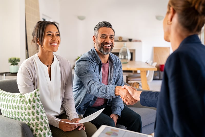 People shake hands with a loan officer while closing on an investment property.