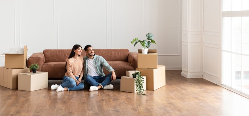 A man and a woman smile while moving into a new home.