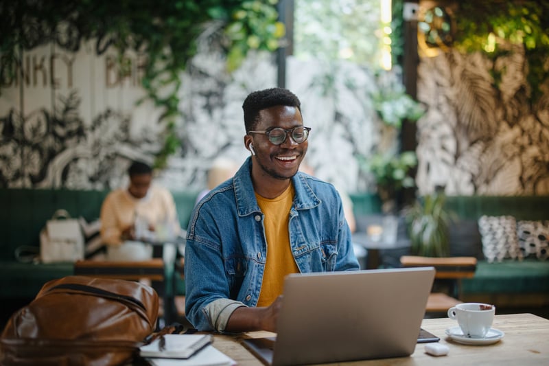 A man smiles at a laptop while he 