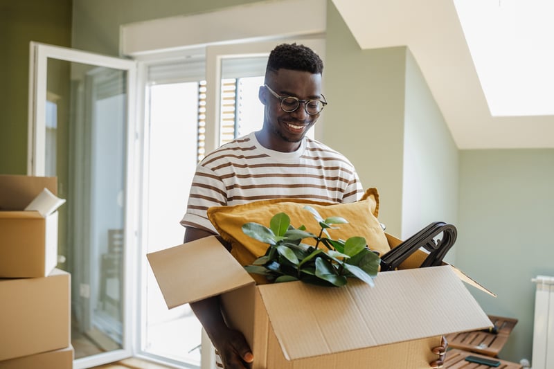 A man carries boxes into a new house.