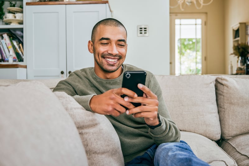 A man smiles while applying for a conventional loan on his phone.