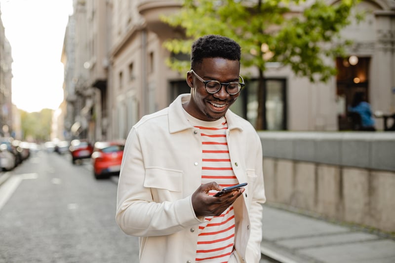 A man smiles while looking at a phone.