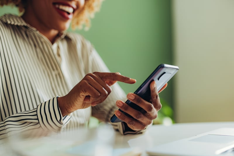 A woman smiles while using a phone to apply for a home equity loan.