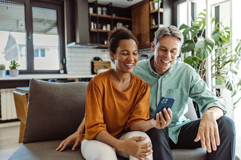 A couple smiles while looking at a cell phone.