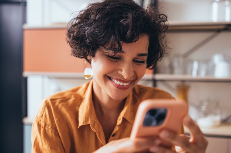 A woman smiles at a phone while applying for a 5/6 ARM.