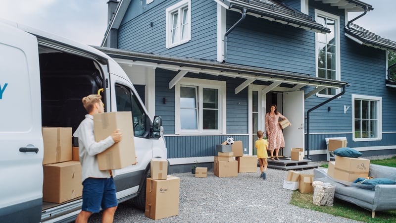 Two people move into a blue wooden house.