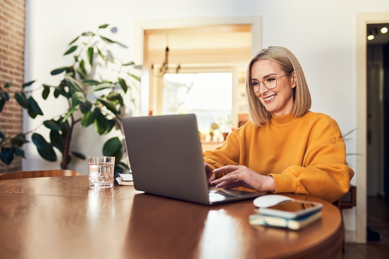A woman smiles at a laptop.