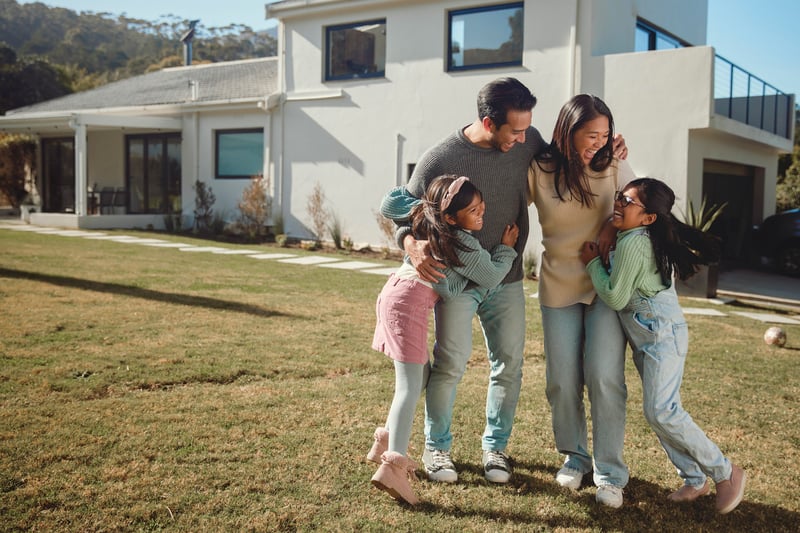 A family hugs each other on the lawn of their second home.