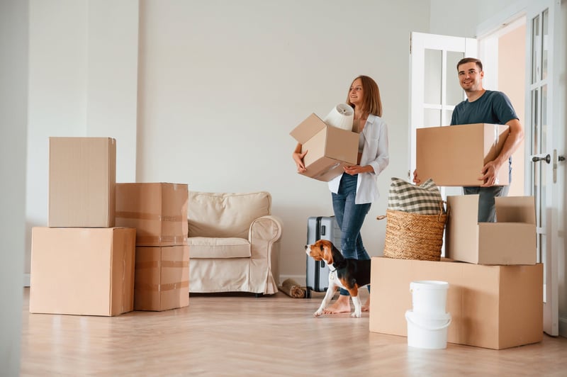 A man and woman carry boxes into a new house.