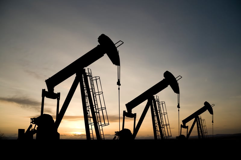 hThree pumpjacks on a prairie at sunrise.