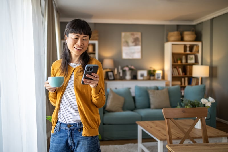 A woman smiles at her phone while exploring refinance options.