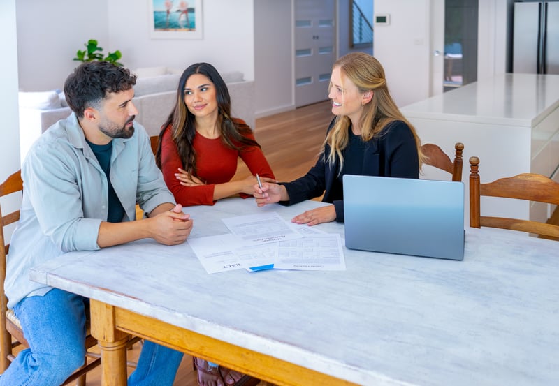 People smile while signing mortgage closing documents.
