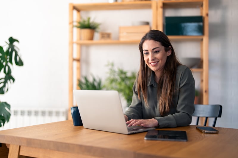 A woman smiles at a laptop.