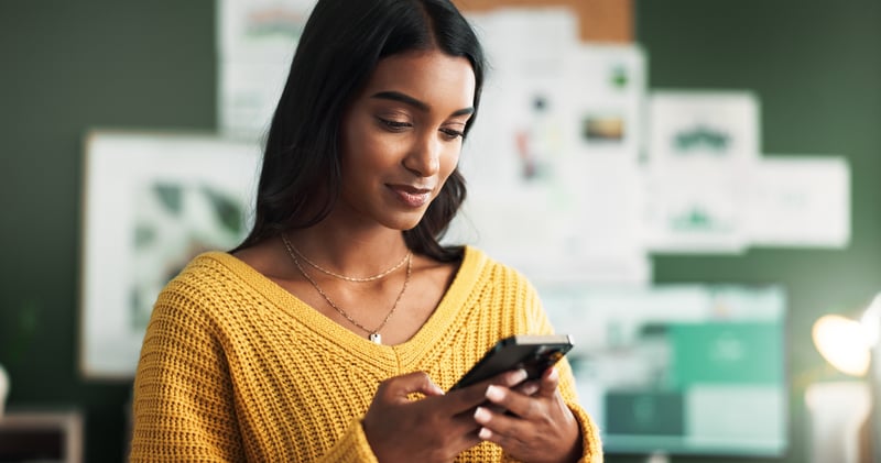 A woman smiles while looking at her phone and evaluating loan options for borrowers with a high DTI.