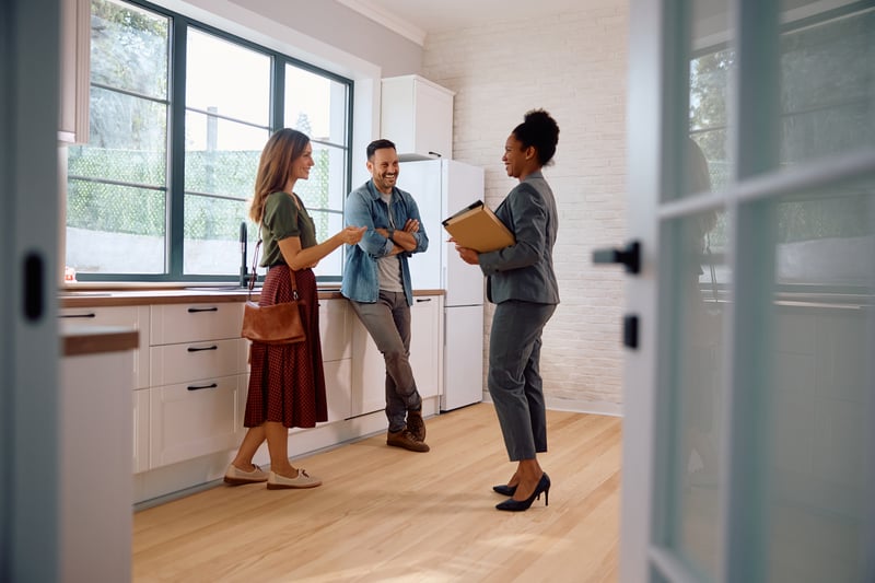 A man and woman speak with a real estate agent.