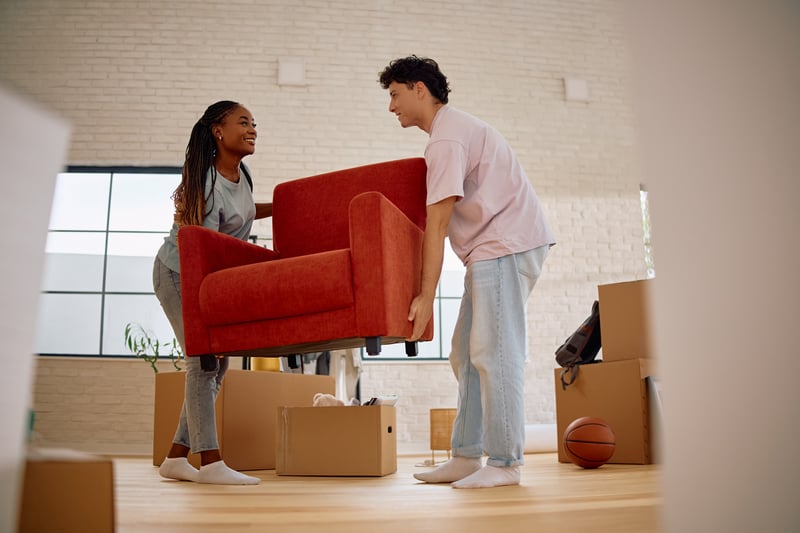 A man and a woman move a chair into a house.