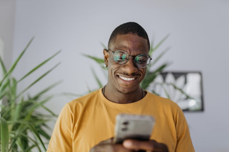 A man smiles at his phone while exploring VA funding fee exemptions.