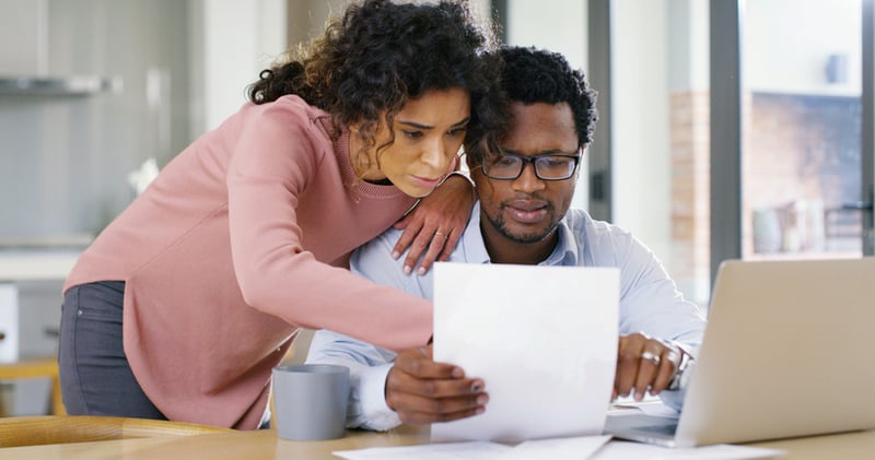 A man and a woman look at a paper.