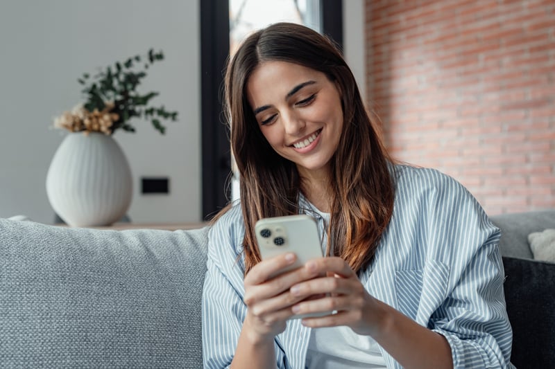 A woman smiles at a phone while learning about HELOC eligibility requirements.