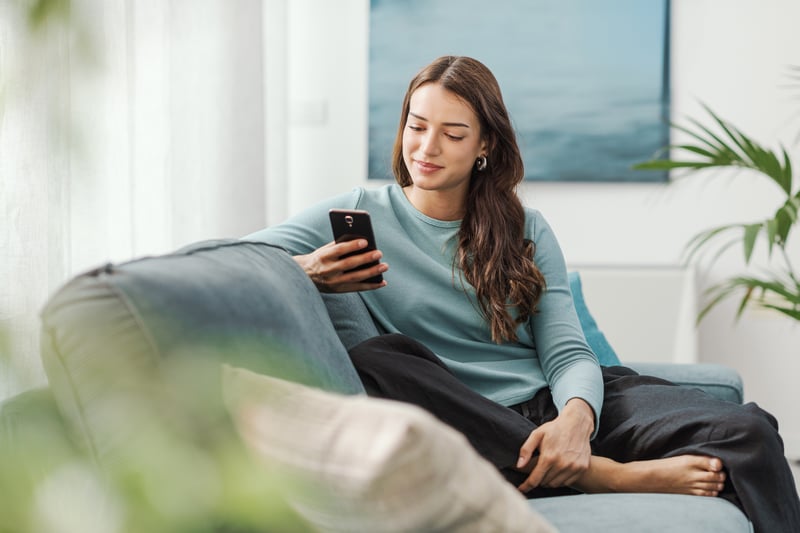 A woman smiles at a phone while exploring HELOC rates.