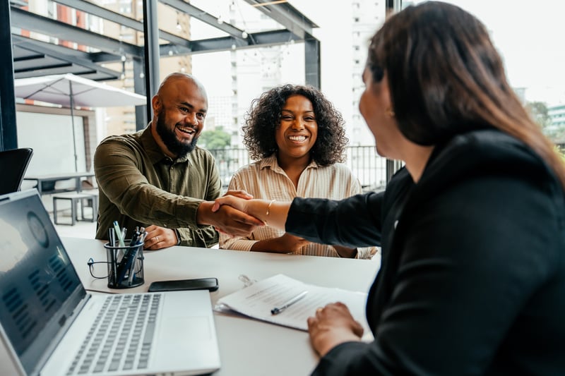 People smile while signing for an investment property.