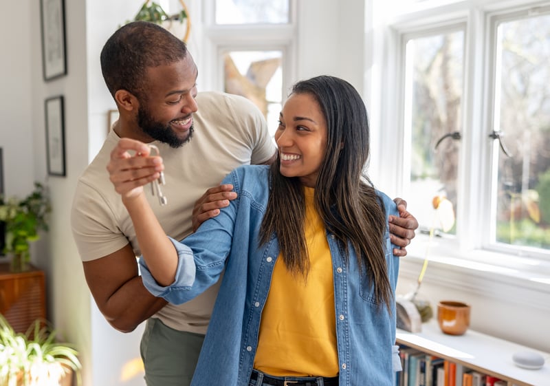 A couple smiles while holding the key to their house
