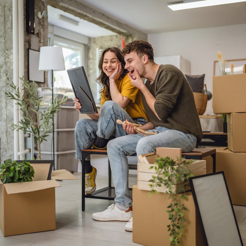 A man and a woman smile while moving into a new house. 