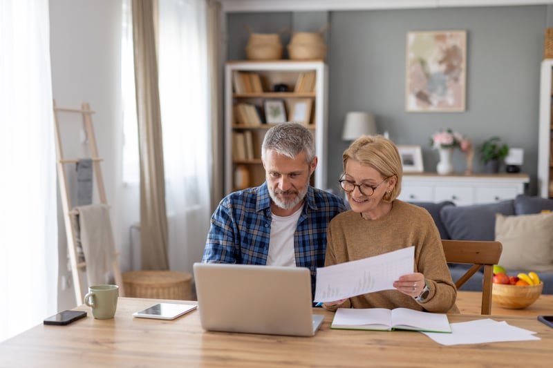 A retired couple looks at home equity options on a laptop.