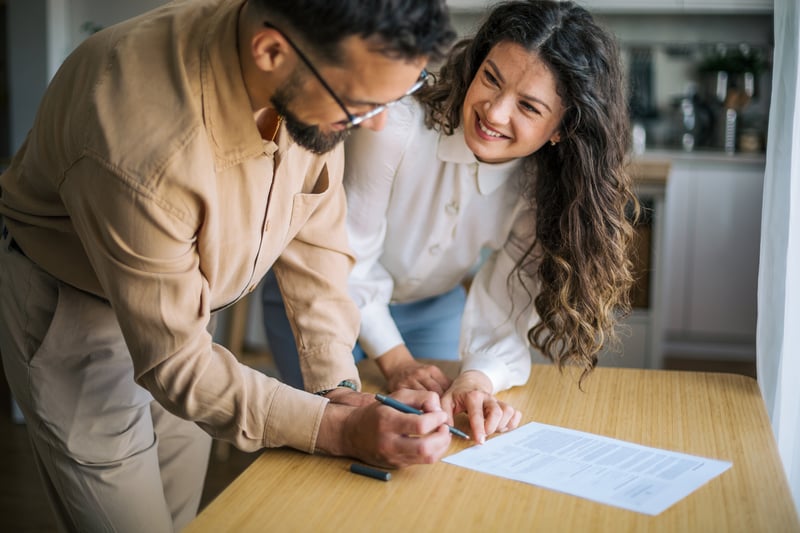 People smile while signing mortgage closing documents.