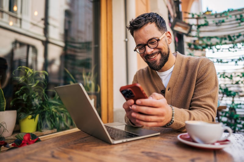 A man smiles at a cell phone.