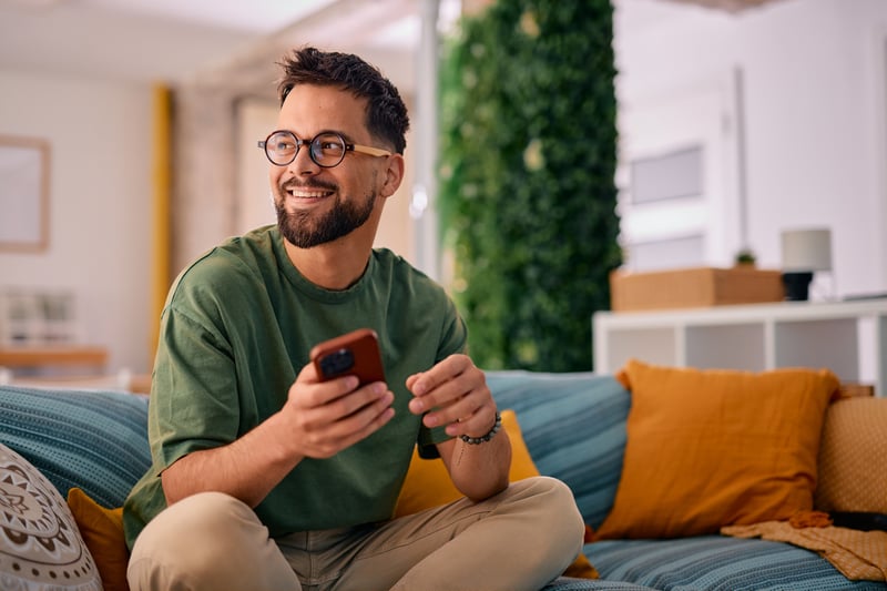 A man smiles while looking at HELOC options on his phone.