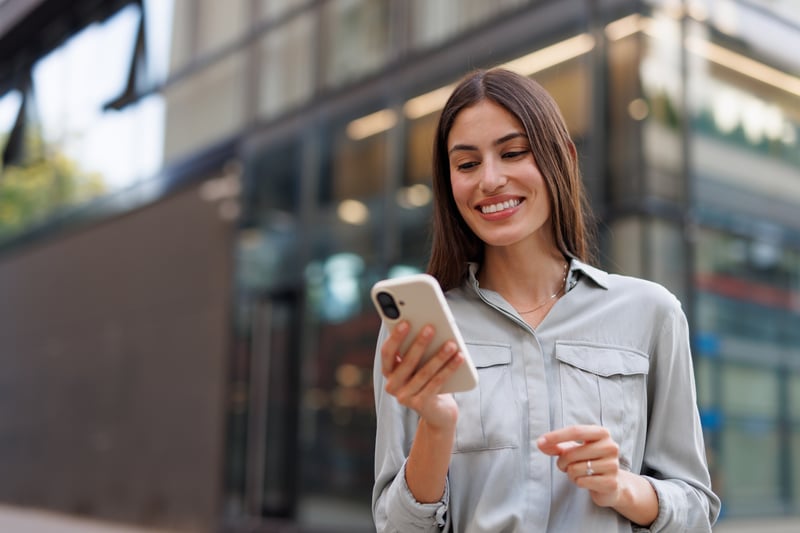A woman smiles at a phone while looking at options to consolidate debt with home equity.