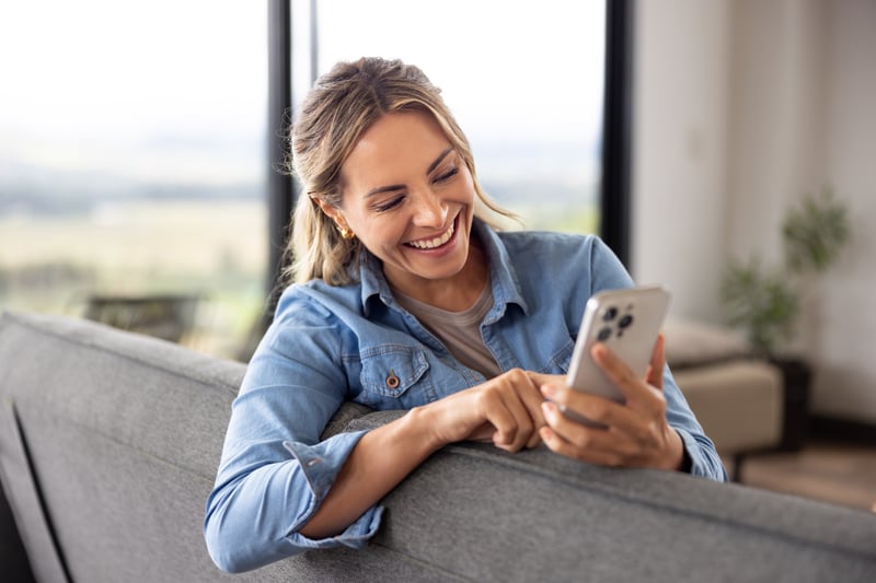 A woman smiles at a phone.