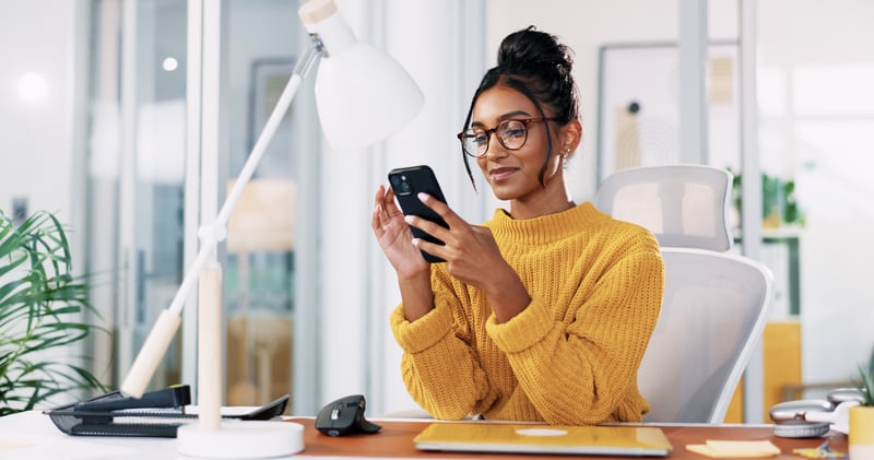 A woman smiles at a phone while comparing interest-only mortgage options.