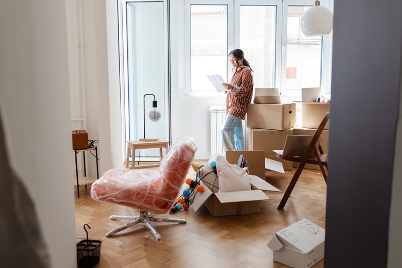 A woman moves boxes and furniture into a new home.