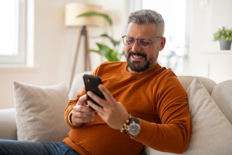 A man smiles while looking at Pennsylvania refinance rates.
