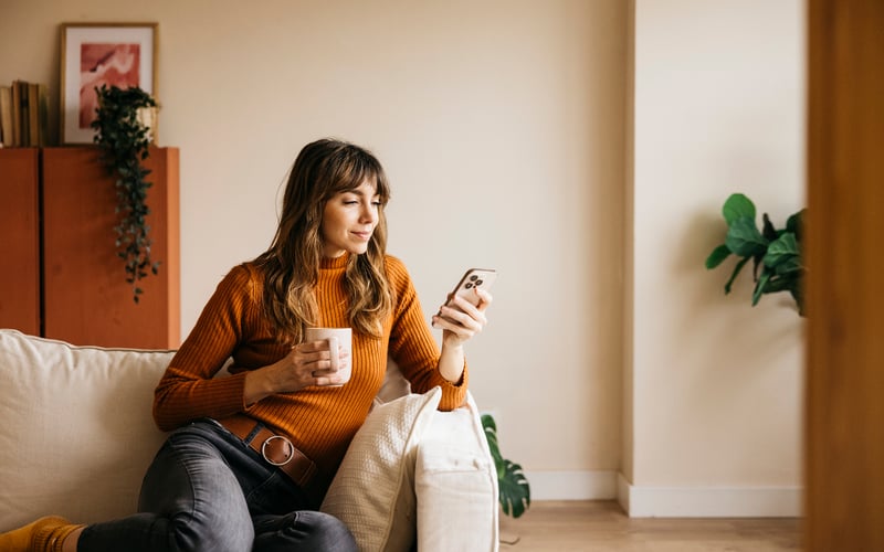 A woman smiles at a phone.