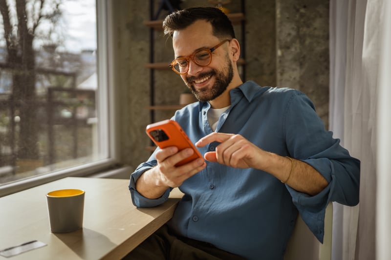 A man smiles at a cell phone.