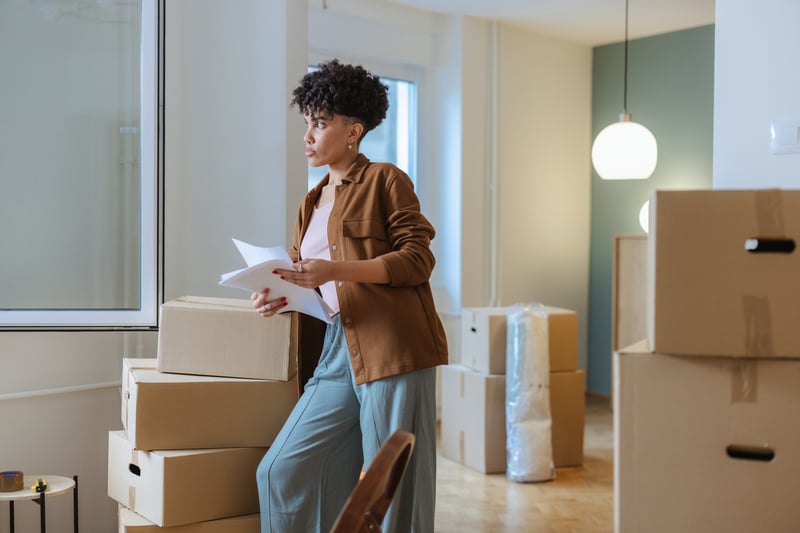 A woman holds documents while moving into a house.