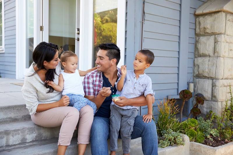 A family smiles outside of their newly purchased second home.