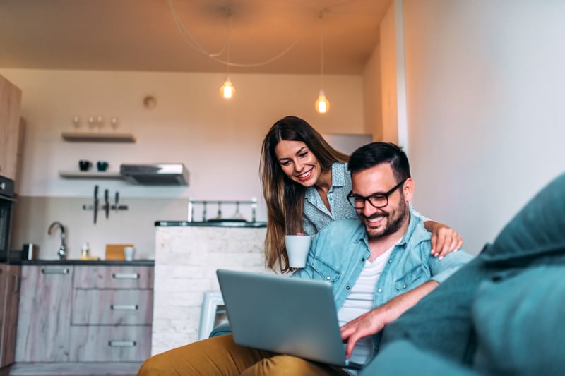 A man and a woman smiling at a laptop